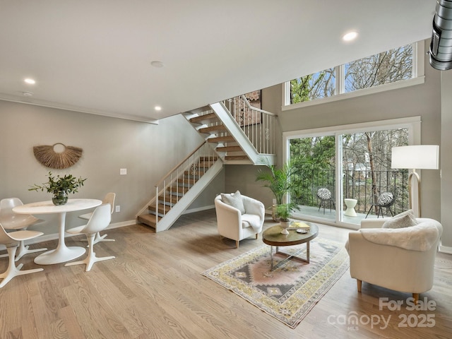 living area with recessed lighting, baseboards, wood finished floors, and stairs