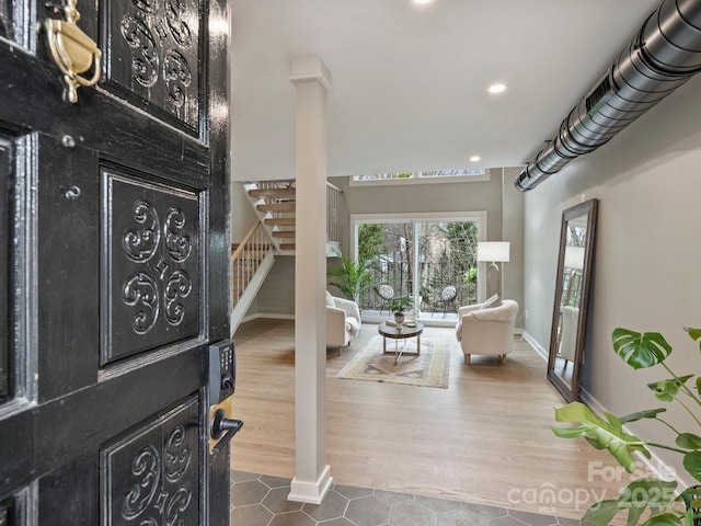 entryway with decorative columns, baseboards, wood finished floors, and stairway