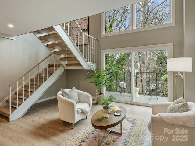 living area featuring stairs, recessed lighting, wood finished floors, and a towering ceiling