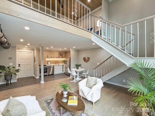 living room with recessed lighting, decorative columns, wood finished floors, and stairs