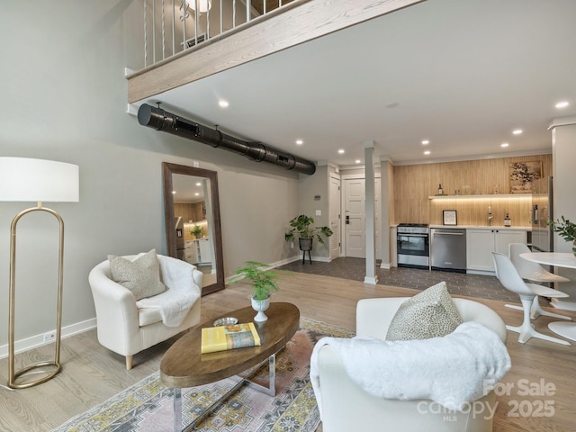 living room featuring recessed lighting, light wood-type flooring, baseboards, and decorative columns