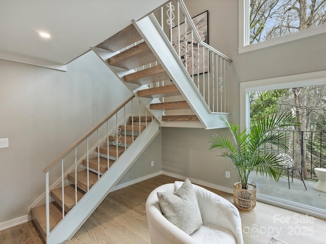 stairway featuring recessed lighting, wood finished floors, baseboards, and a wealth of natural light