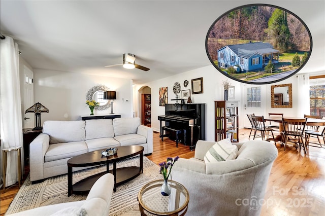 living area with a ceiling fan, arched walkways, and wood finished floors