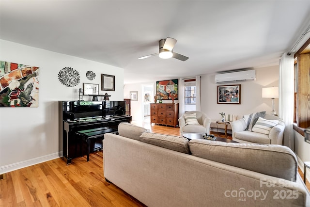 living room featuring light wood finished floors, baseboards, a ceiling fan, and a wall mounted air conditioner