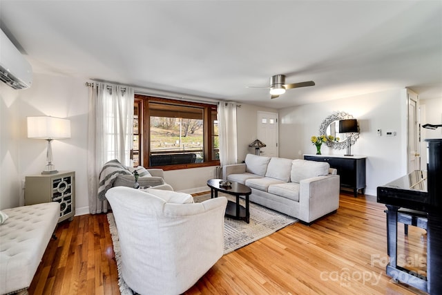 living room with a ceiling fan, baseboards, wood finished floors, and a wall mounted air conditioner