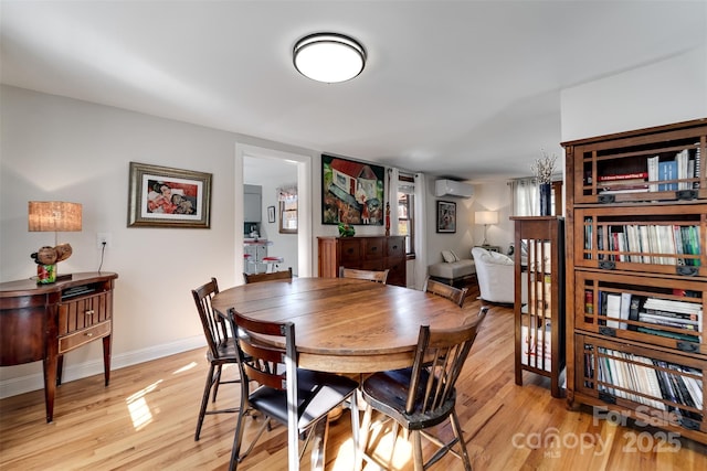 dining area with light wood-type flooring, baseboards, and a wall mounted AC