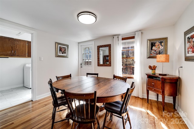 dining space with washer / dryer, light wood-style flooring, and baseboards