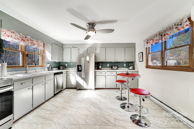 kitchen featuring a baseboard radiator, marble finish floor, stainless steel appliances, light countertops, and backsplash