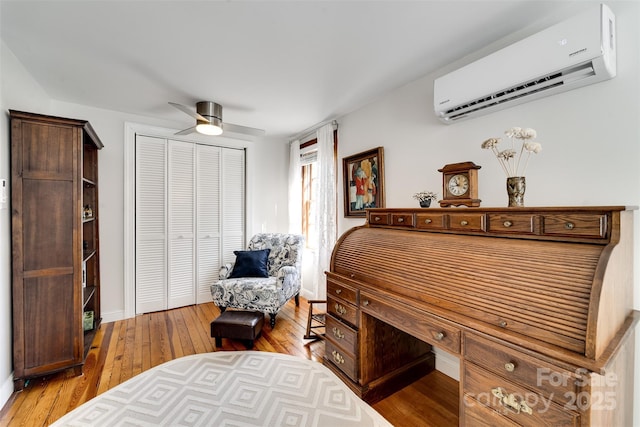 bedroom with light wood-type flooring, a ceiling fan, a closet, and a wall mounted air conditioner