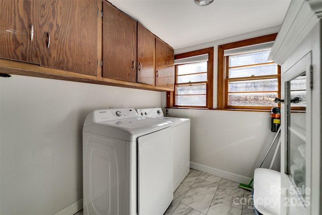 washroom featuring marble finish floor, washer and clothes dryer, cabinet space, and baseboards