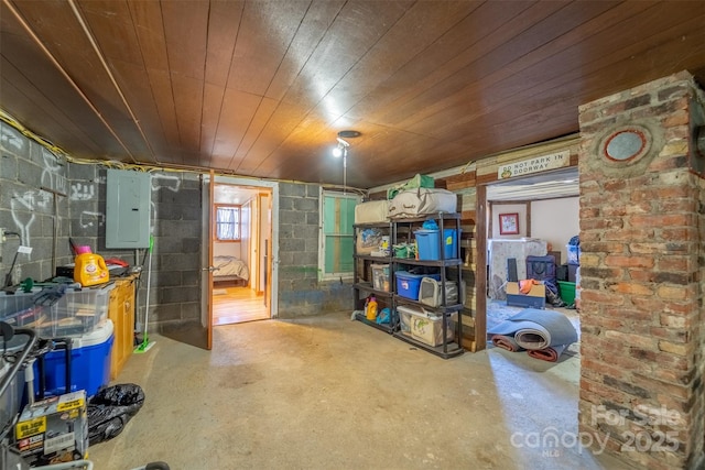 finished basement with wooden ceiling, electric panel, and concrete block wall