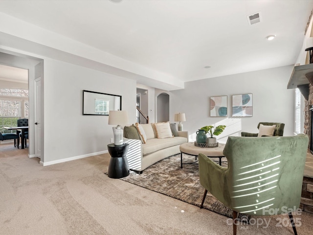 living room with arched walkways, baseboards, visible vents, and carpet