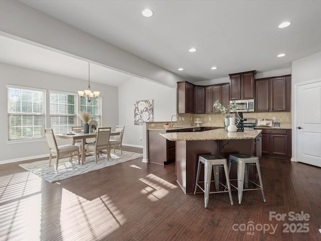 kitchen featuring dark brown cabinets, backsplash, a center island, dark wood-style floors, and stainless steel microwave