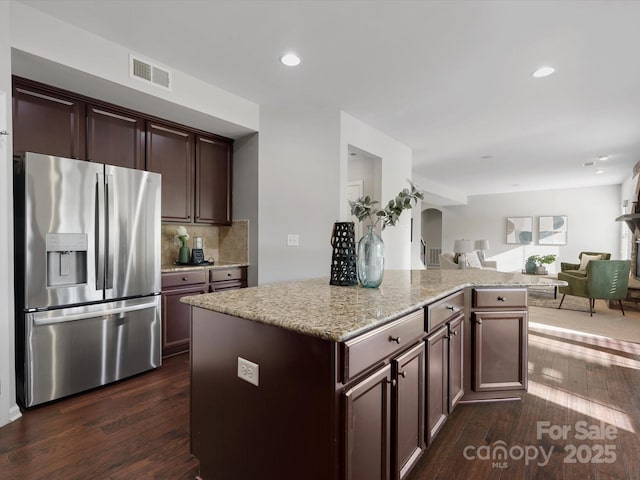 kitchen featuring arched walkways, dark wood-type flooring, visible vents, open floor plan, and stainless steel fridge with ice dispenser