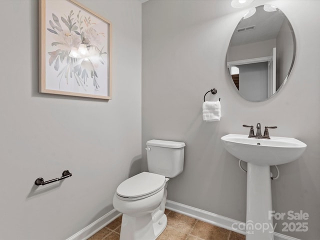 half bath featuring toilet, tile patterned flooring, visible vents, and baseboards