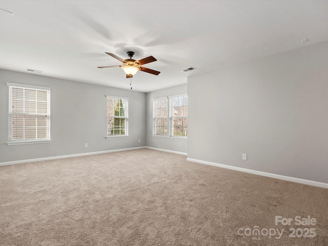 empty room featuring a ceiling fan, carpet flooring, visible vents, and baseboards