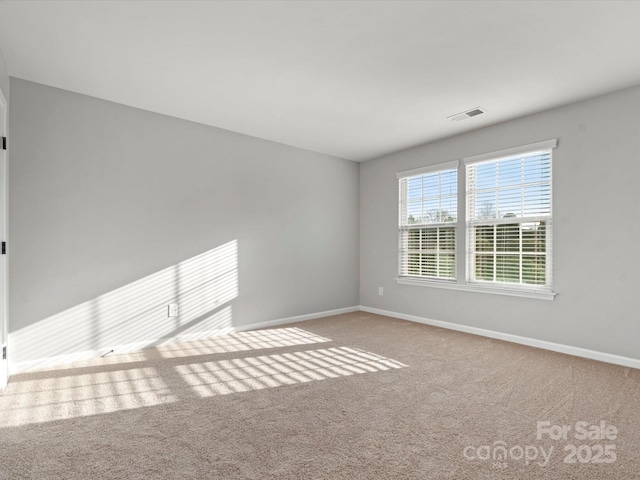 carpeted spare room featuring visible vents and baseboards