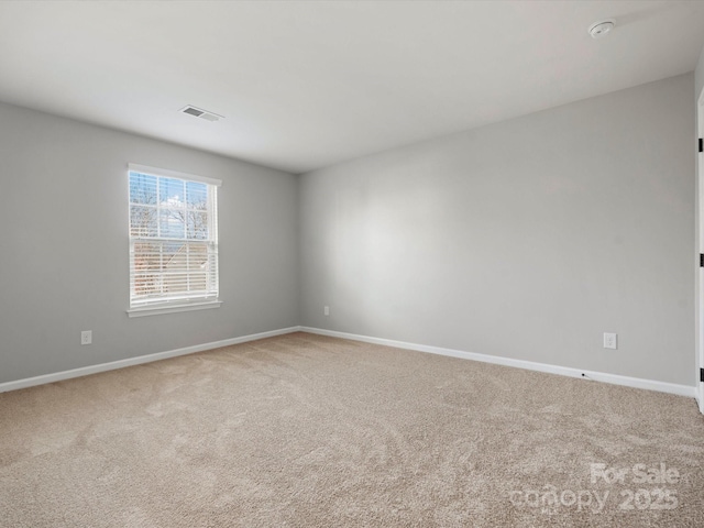 spare room featuring carpet flooring, visible vents, and baseboards