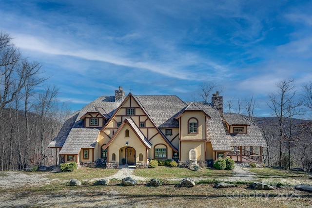 english style home with a chimney and stucco siding