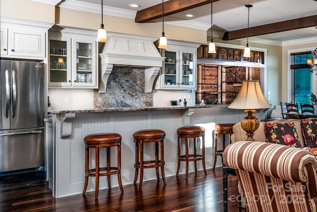 kitchen featuring decorative backsplash, a kitchen breakfast bar, dark wood-style flooring, freestanding refrigerator, and beam ceiling