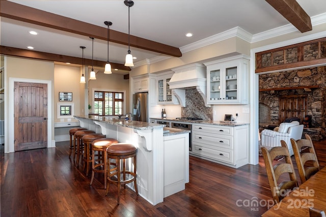 kitchen with dark wood finished floors, light stone counters, stainless steel appliances, premium range hood, and beam ceiling