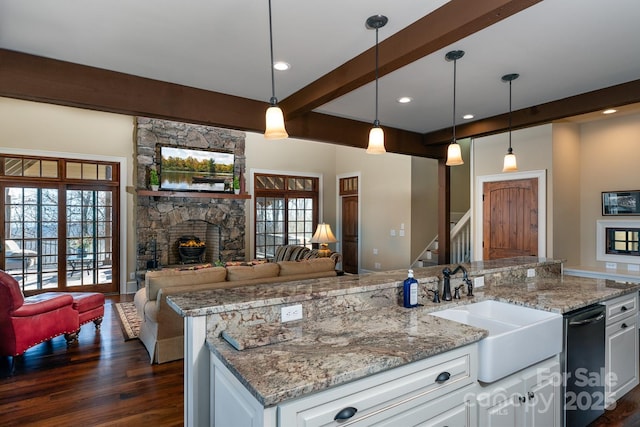 kitchen featuring dark wood-type flooring, a fireplace, a sink, open floor plan, and beam ceiling