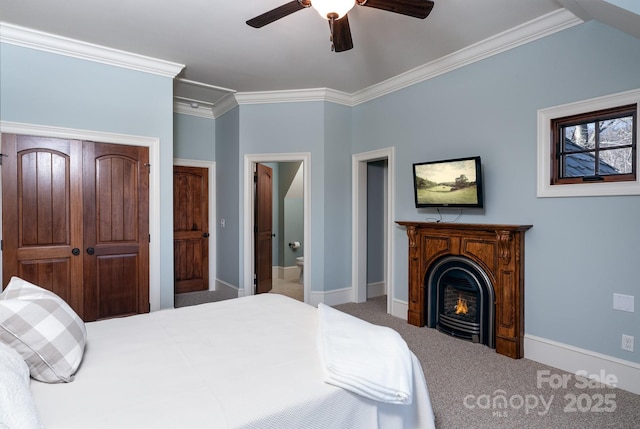 bedroom featuring a warm lit fireplace, carpet, baseboards, and crown molding