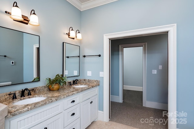 full bathroom with baseboards, double vanity, a sink, and crown molding