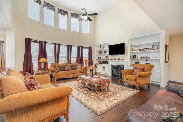 living area featuring decorative columns, a healthy amount of sunlight, dark wood finished floors, and a fireplace