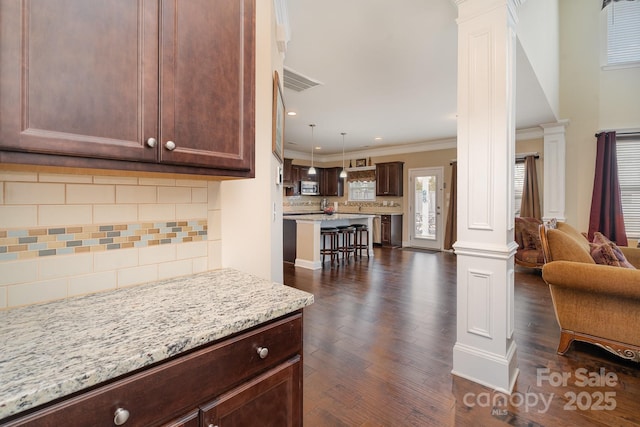 kitchen with dark wood-type flooring, a breakfast bar, and ornate columns