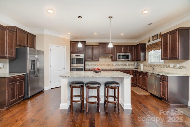 kitchen featuring dark brown cabinets, a kitchen island, under cabinet range hood, and stainless steel appliances