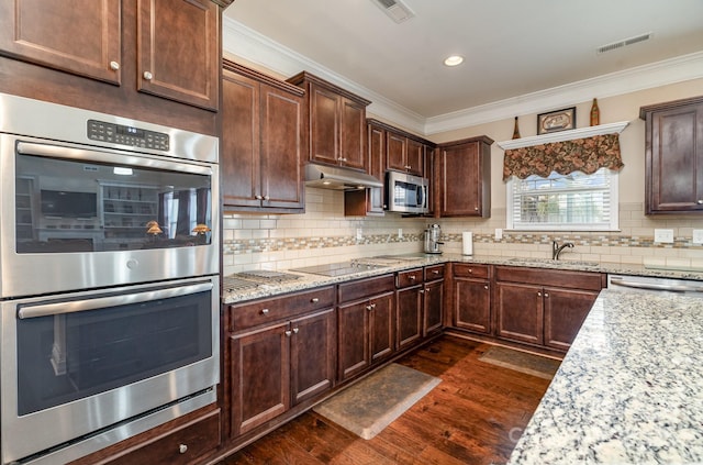 kitchen with visible vents, dark wood finished floors, appliances with stainless steel finishes, under cabinet range hood, and crown molding