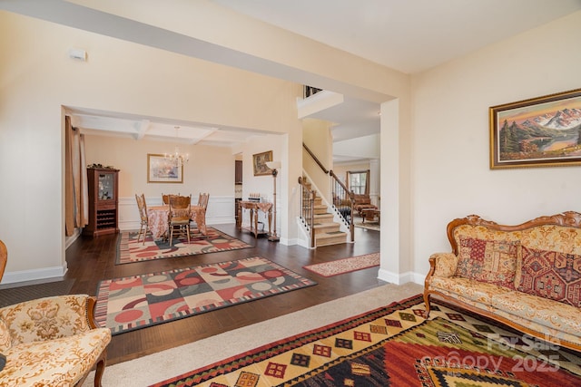 living room featuring beamed ceiling, a notable chandelier, hardwood / wood-style flooring, coffered ceiling, and stairs