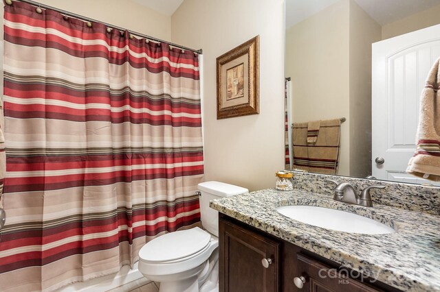 bathroom with curtained shower, toilet, and vanity