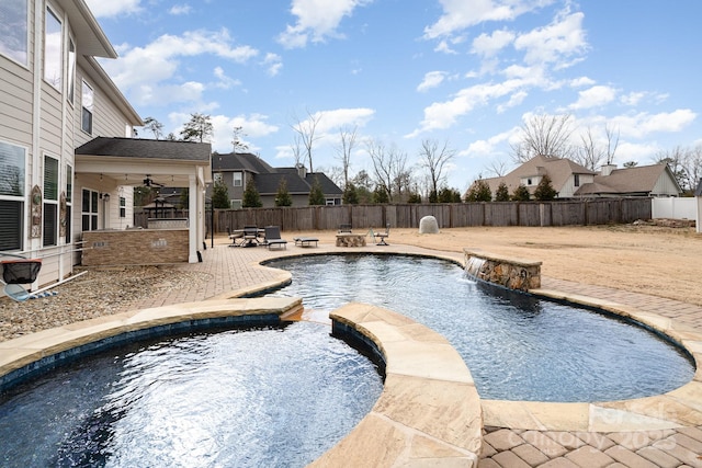 view of swimming pool with a patio, a fenced backyard, a pool with connected hot tub, and ceiling fan