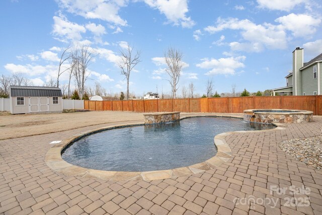 view of swimming pool with an outdoor structure, a fenced backyard, a pool with connected hot tub, and a patio