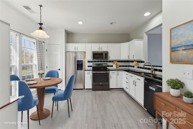 kitchen featuring tasteful backsplash, visible vents, dark countertops, stainless steel appliances, and a sink