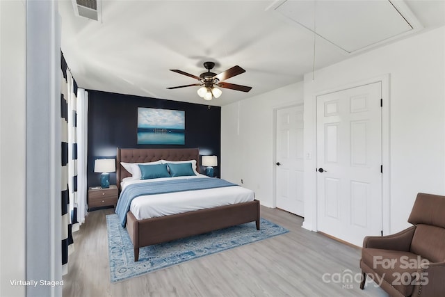 bedroom featuring visible vents, ceiling fan, wood finished floors, and attic access