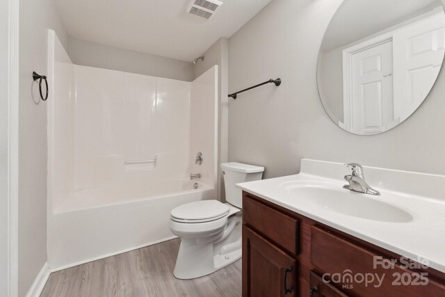 full bath with shower / tub combination, toilet, wood finished floors, vanity, and visible vents