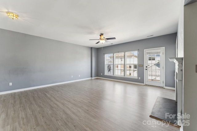 unfurnished living room featuring ceiling fan, baseboards, and wood finished floors