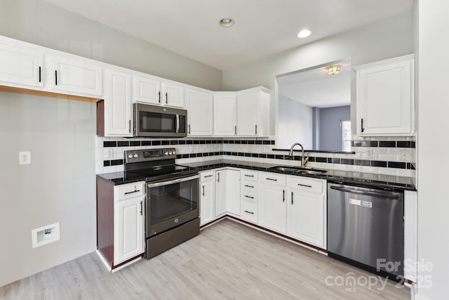 kitchen featuring stainless steel appliances, light wood-style floors, white cabinets, and a sink