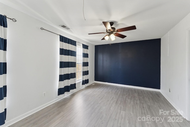 empty room featuring visible vents, baseboards, and wood finished floors