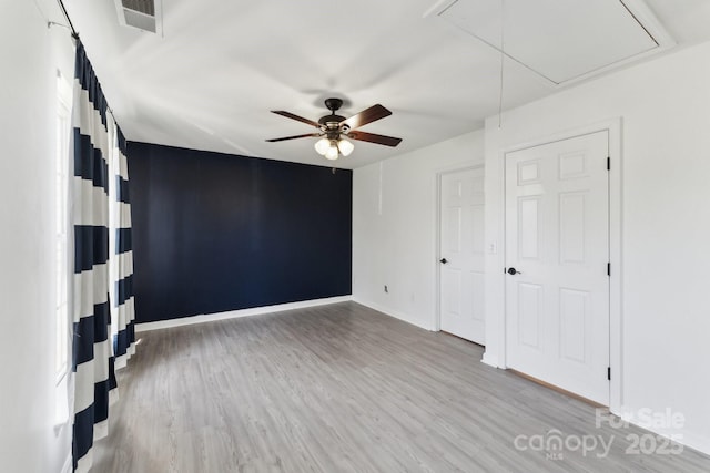 unfurnished room featuring visible vents, a ceiling fan, baseboards, light wood-type flooring, and attic access