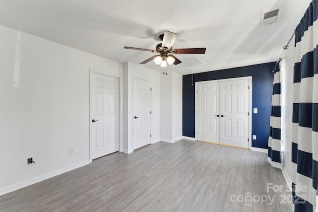 unfurnished bedroom with a closet, visible vents, light wood-style floors, a ceiling fan, and baseboards