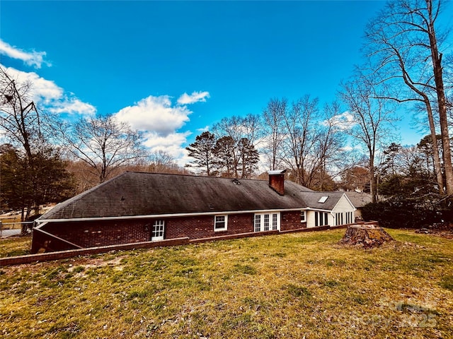 view of home's exterior with a yard, brick siding, and a chimney