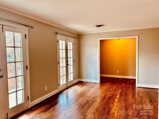 spare room featuring visible vents, ornamental molding, wood finished floors, and french doors