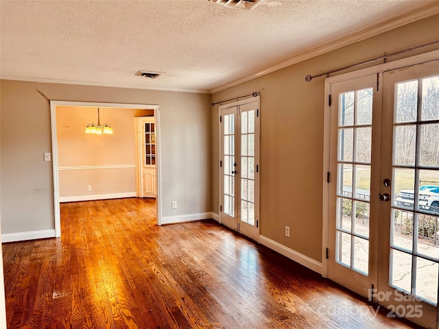 interior space with french doors, visible vents, ornamental molding, a textured ceiling, and wood finished floors