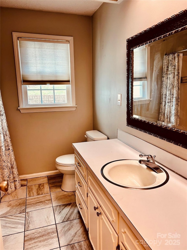 bathroom featuring a shower with shower curtain, baseboards, vanity, and toilet