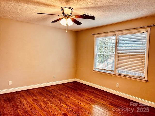 spare room featuring dark wood-style flooring, a textured ceiling, and baseboards