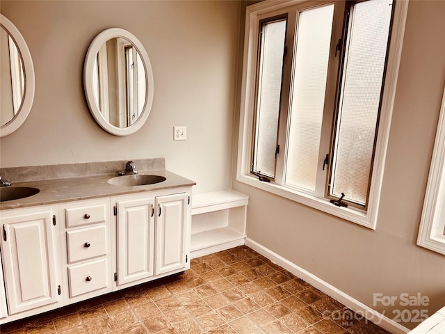 bathroom with double vanity, a sink, and baseboards